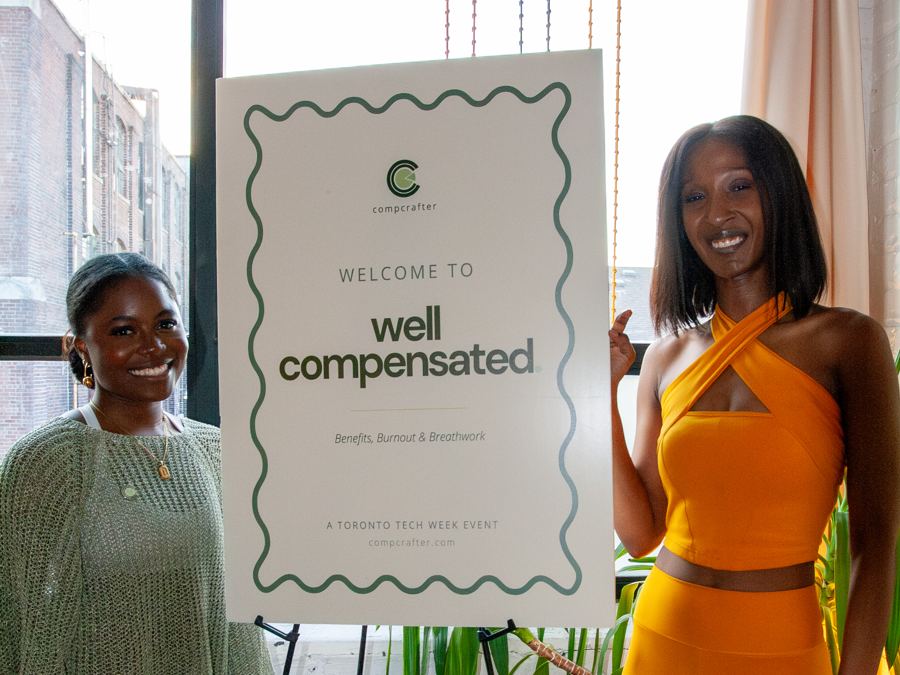 Two guests beside the welcome sign at Well Compensated, a CompCrafter event