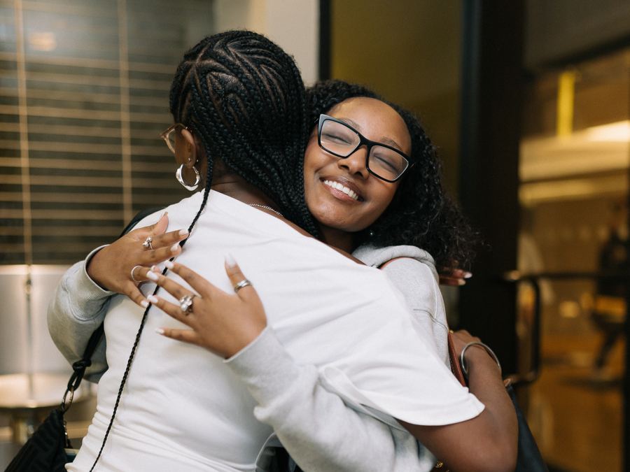 Two guests hugging at a Well Compensated event